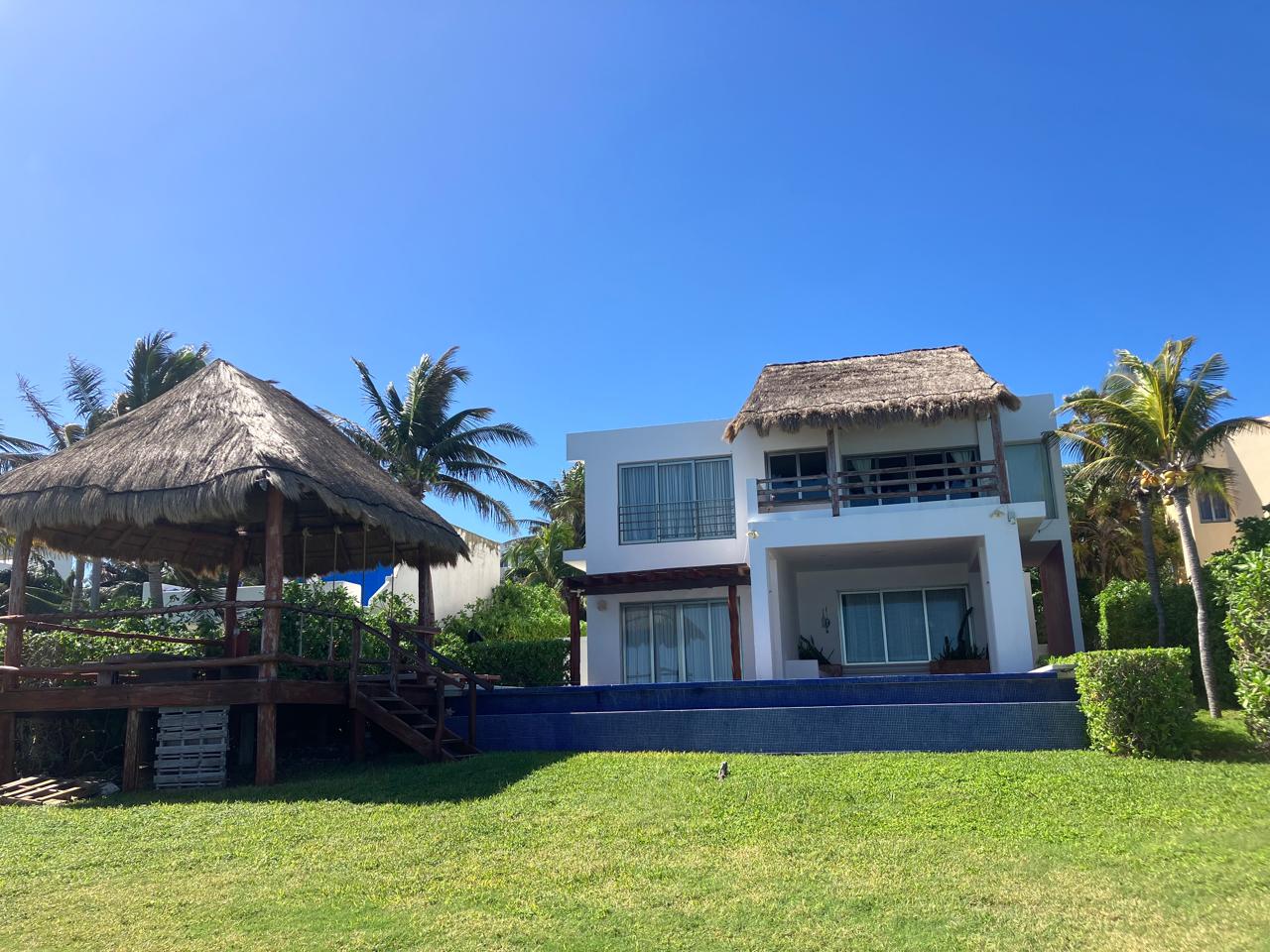 Fachada de la villa con alberca y palapa